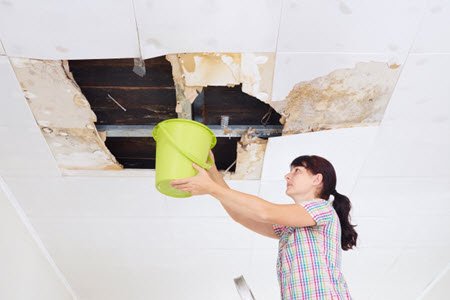 woman with bucket for leaky ceiling